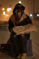 A homeless woman begs in Detroit, Michigan, where more job losses are imminent should the US car industry collapse.