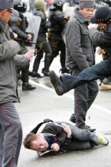 A plain-clothes policeman kicks an anti-government protester in Bishkek.