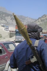 Rocky progress...an Afghan with a rocket-propelled grenade launcher watches traffic on the Khost-Gardez road.