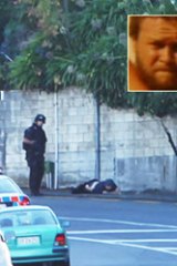 Suburban violence ... a man lies injured on the road, directly opposite where the gunman opened fire.