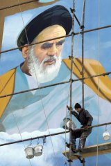 Keeping watch &#8230; a painter works on an election mural of the Iranian revolutionary leader, Ayatollah Khomeini, in Tehran.