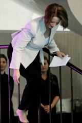 Prime Minister Julia Gillard places her foot back into her shoe after losing it walking on stage.