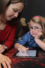 Coco Maslin, 4, with researcher Leila Dafner, loves colouring in pictures on her iPad.