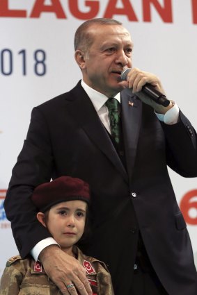 Turkish President Recep Tayyip Erdogan stands with a young girl in military uniform as he speaks to his ruling party members, in Kahramanmaras, Turkey.