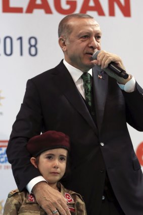 Turkish President Recep Tayyip Erdogan stands with a young girl in military uniform as he speaks to his ruling party members, in Kahramanmaras, Turkey.