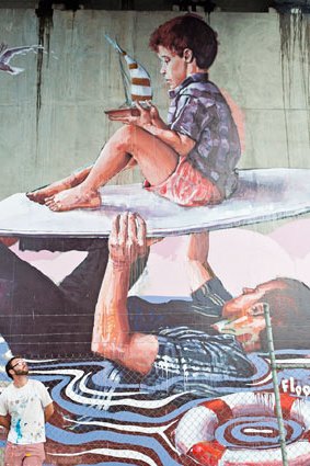 Artist Fintan Magee with his work on a South Brisbane pillar, done as part of G20 cultural celebrations.