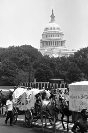 People walk beside wagons of the mule train of the Poor People's Campaign as it makes its way through Washington on June 25, 1968.