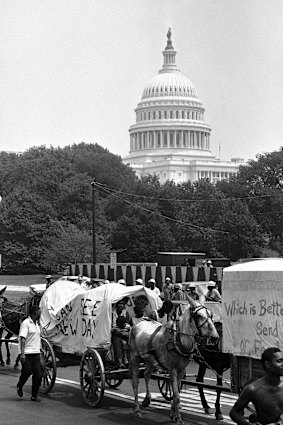 People walk beside wagons of the mule train of the Poor People's Campaign as it makes its way through Washington on June 25, 1968.