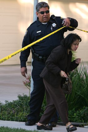 A Santa Clara police officer allows a neighbour to leave the area where six people were killed.