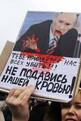 A woman holds a sign depicting Russian President Vladimir Putin as the devil with text reading "You will have to kill all of us, not choke us with our blood" during a demonstration entitled "Ukraine and Crimea are together" in Kiev.