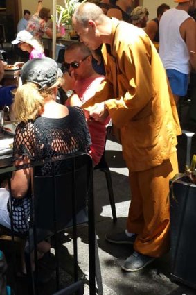 A man dressed as a monk approaches someone in Circular Quay.