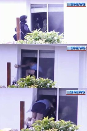 Police help a woman out of a Banyo house during a siege on Boxing Day.
