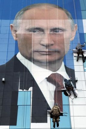 Workers putting up a Putin poster.