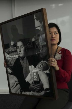 Exhibition curator Kim Tao with a photo of mother and child bound for Australia in the 1950s.