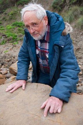Dr Tom Rich reveals a dinosaur footprint at Melanesia Beach.