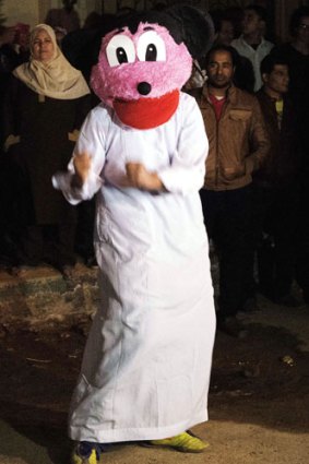 Egyptian youth perform the Internet craze, the "Harlem Shake" in a Mickey Mouse mask.