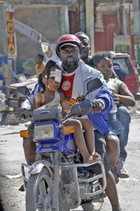 Anxious ride ... a family takes an injured girl to one of the few hospitals still operating in Port-au-prince, which is covered in a shroud of white from the rubble.