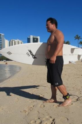 Rudy Aguilar models the Electronic Shark Defense System, a shark deterrent device that attaches to his ankle and surfboard, in Honolulu, Oahu.
