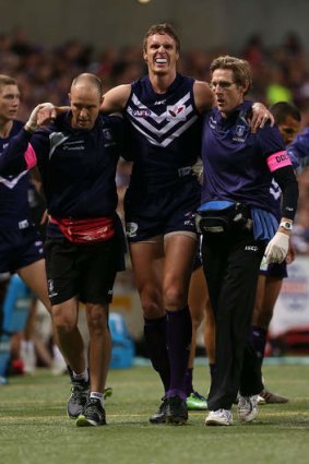 Jon Griffin of the Dockers is assisted from the field after injuring his knee.