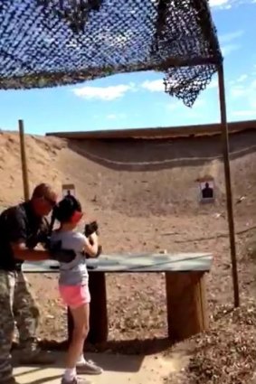 Shooting instructor Charles Vacca stands next to a 9-year-old girl at the Last Stop shooting range at Bullets and Burgers in White Hills, Arizona.