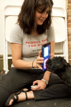 Anna Grossman holds her iPad while her dog Amos touches the screen with his nose.