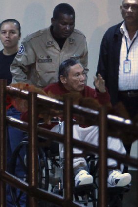 A police officer wheels former dictator Manuel Noriega into El Renacer prison in Panama City.