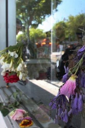 Flowers fill bullet holes in the shop front where Elliot Rodger fired shots.