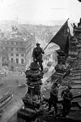 The three soldiers fly the Soviet flag over the Reichstag.