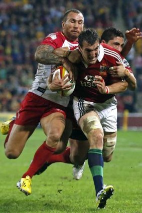 Hold on there: The Lions' Sam Warburton is tackled by Quade Cooper.