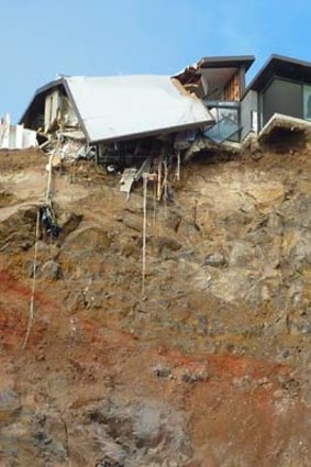 Damaged houses cling to the cliff near Sumner, outside the city.