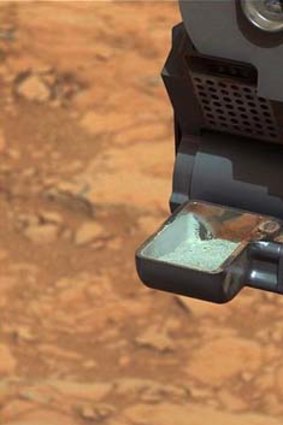 Futher evidence of conditions conducive to life: The Curiosity rover holds a scoop of powdered bedrock.