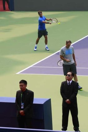 Roger Federer is surrounded by security personnel on court.