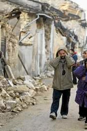 A family walks past damaged buildings the morning after an earthquake struck the Italian village of Onna on April 7, 2009.