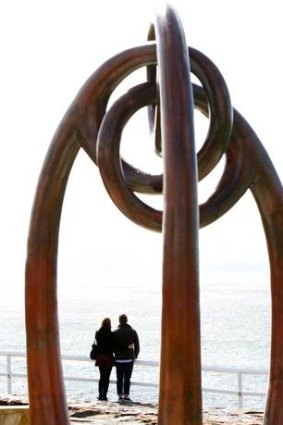 A couple pause to reflect near the memorial sculpture at Dolphin Point, Coogee.