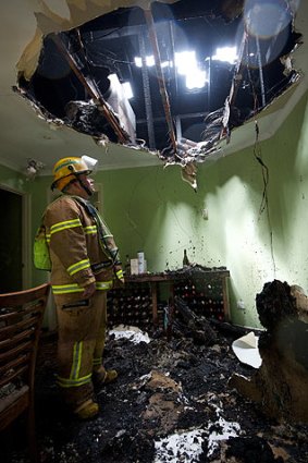 Incoming ... A firefighter stands under a hole blasted through the roof of a house in Berwick by a lightning strike.