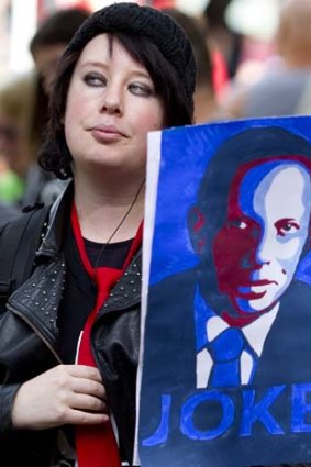 A protester holds a placard depicting Tony Abbott.