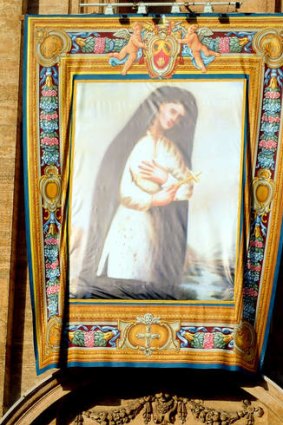 This be a saint ... the tapestry of Kateri Tekakwitha hangs on St Peter's Basilica during the special Mass to name seven new saints.