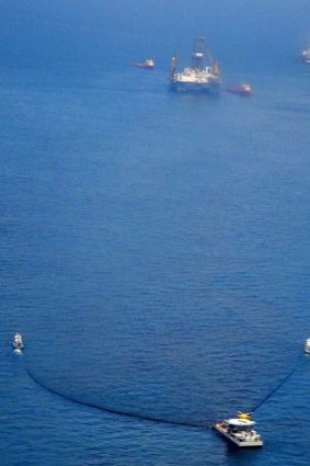 Tug boats, bottom, pull oil absorbing boom towards the Deep Sea Horizon oil spill site, top, in the Gulf of Mexico.