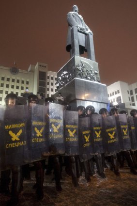 Riot police standing under a monument of Russian revolutionary and politician Vladimir Lenin.