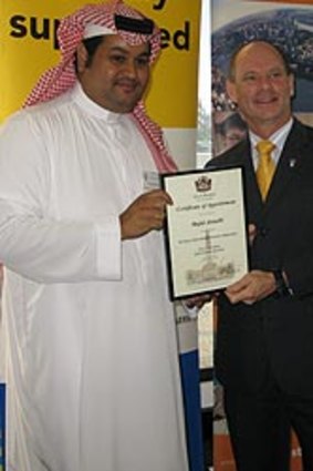 UQ computer engineering PhD student Majid Alotaibi of Saudi Arabia, in traditional clothing, receives his certificate from Lord Mayor Campbell Newman.