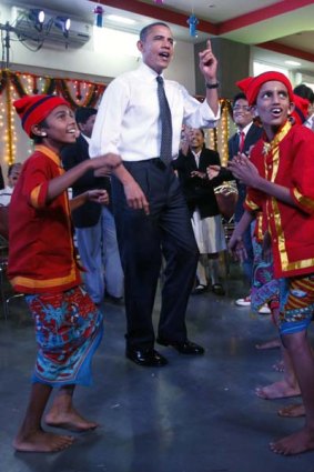 Getting into the local rhythm ... Barack Obama and Michelle Obama dance with children during a visit to the Holy Name High School in Mumbai.