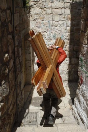A pilgrim carries a large wooden cross along the Via Dolorosa during Holy Week.