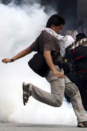 A demonstrator in Kuala Lumpur tries to kick away a tear-gas canister.
