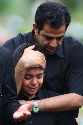 Iranian orphan Seena is comforted by a relative at his parents' funeral.