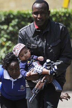 Rescued: A policeman carries a baby to safety after the attack on the Westgate mall.