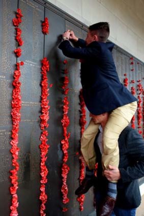 Tribute: Strings of poppies being hung at the Roll of Honour.