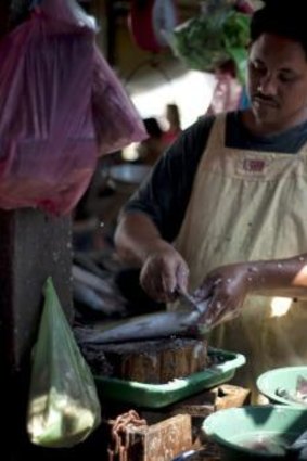 A vendor prepares fish in the Masinloc market.