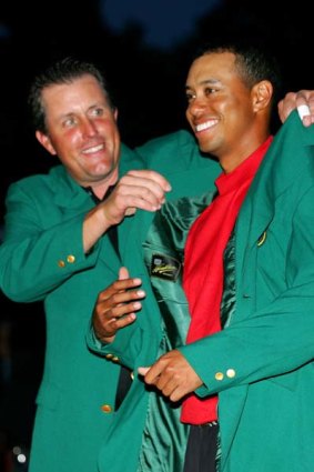 Tiger Woods is presented with the green jacket by Phil Mickelson after Woods won the 2005 US Masters.