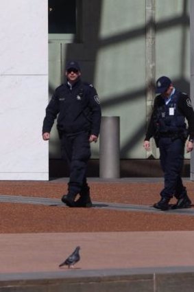 Australian Federal Police officers patrol Parliament House after terrorist threats escalated security concerns.