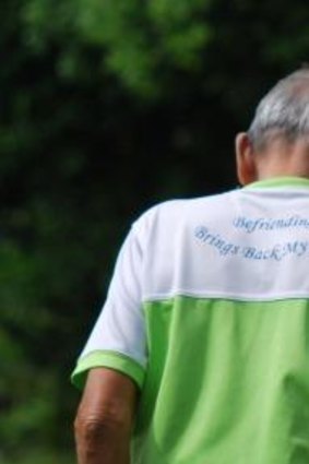 An elderly club member wears a shirt with the slogan "befriending brings back my smile".